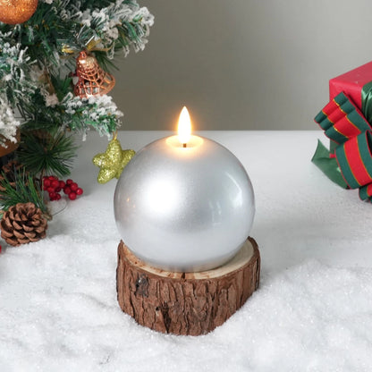 Silver spherical candle on a wooden base with a Christmas tree and gift in the background