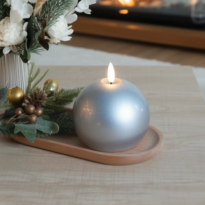 Silver candle on a wooden tray with decorative elements on a table.