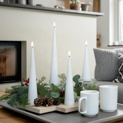 White candles and mugs on a tray with a fireplace and sofa in the background