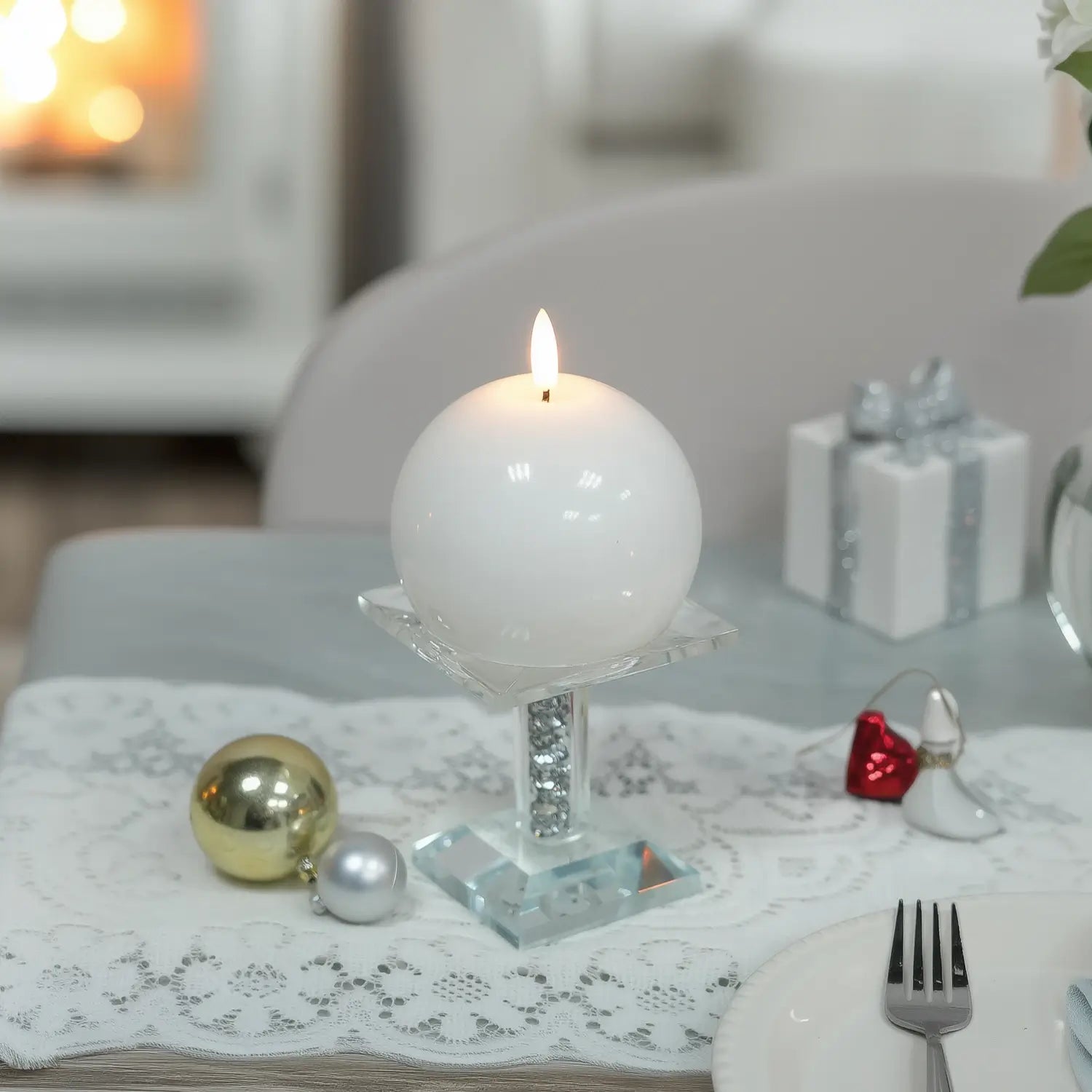 White spherical candle on a concrete tray with flowers on a wooden table
