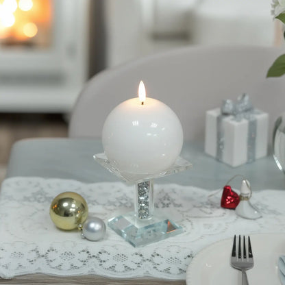 White spherical candle on a concrete tray with flowers on a wooden table
