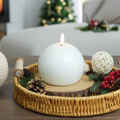White candle on a wooden base surrounded by greenery and pine cones.
