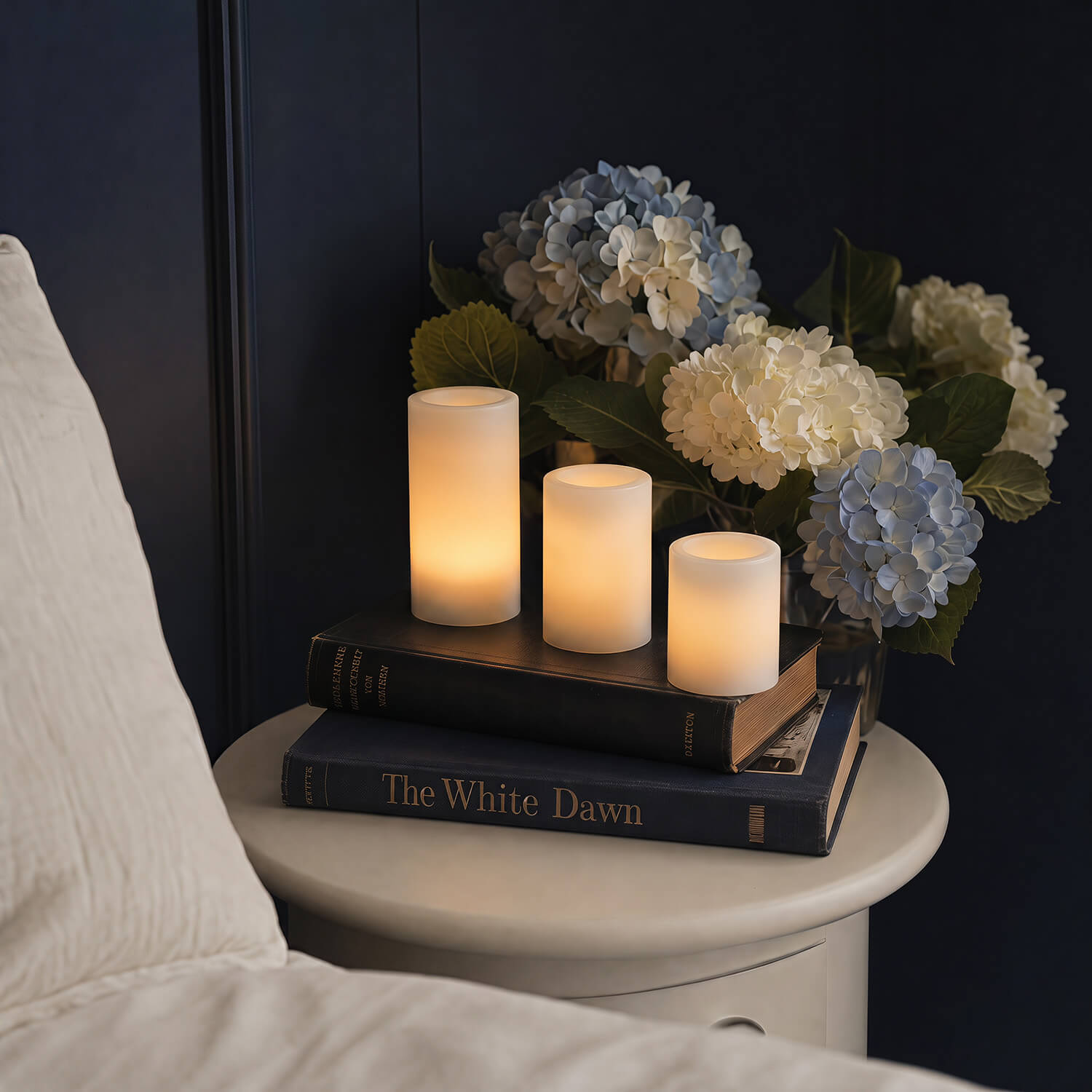Candle holder with three candles and a bouquet of flowers on a nightstand next to a bed.