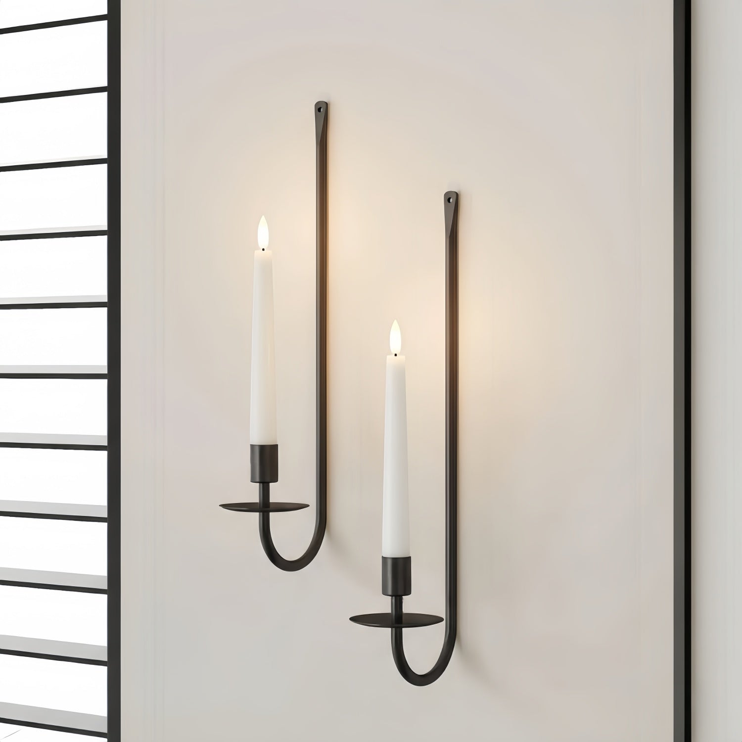 Two wall-mounted candle holders with lit candles on a neutral background