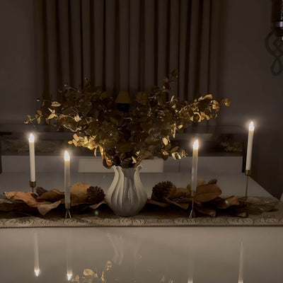 Decorative table setting with candles and a vase of flowers in a dimly lit room.
