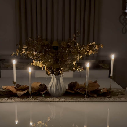 Decorative table setting with candles and a vase of flowers in a dimly lit room.