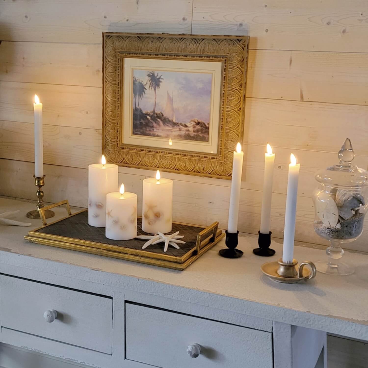 Candles on a wooden surface with a framed picture in the background