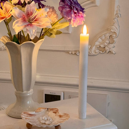 Floral arrangement in a vase with a lit candle on a decorative surface.