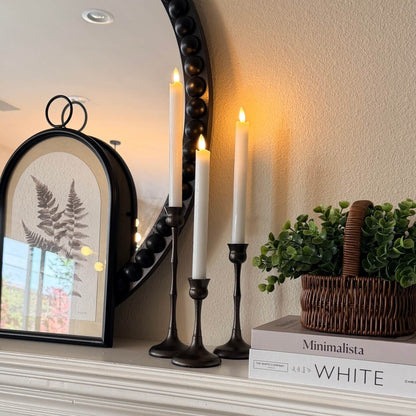 Decorative setup with a mirror, candles, and books on a shelf.