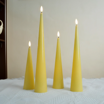 Four yellow taper candles with lit wicks on a textured surface.