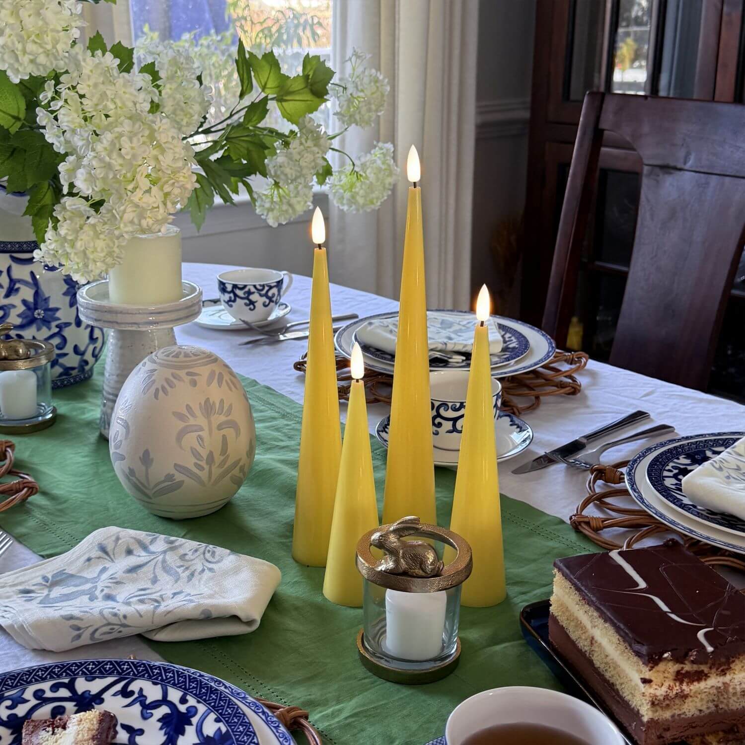 Set of four yellow taper candles on a wooden surface with a neutral background#color_shiny-yellow